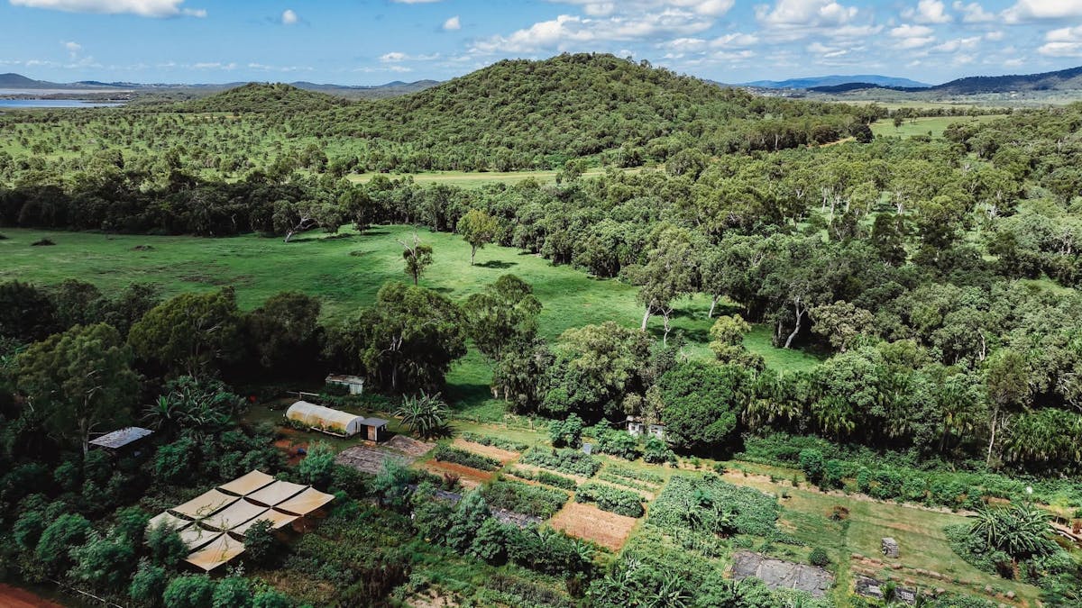 Aerial view of lush permaculture gardens and forested hills at High Valley Dawn near Yeppoon