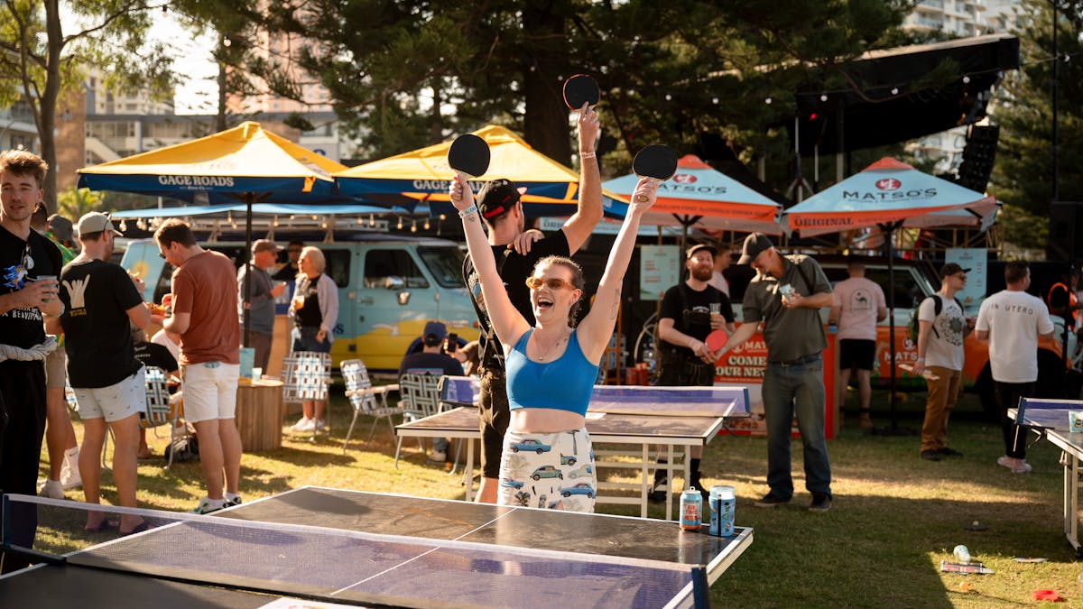 A girl playing ping pong throws her hands in the air