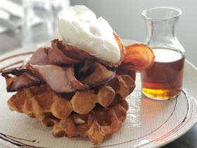 Poached Eggs on Bacon and Waffles with a side of Maple Syrup