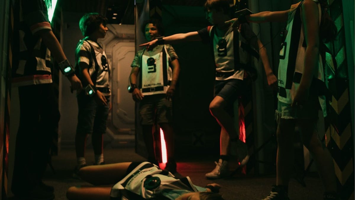 Children in Saboteurs gear point accusingly at each other, one player lying on the floor.