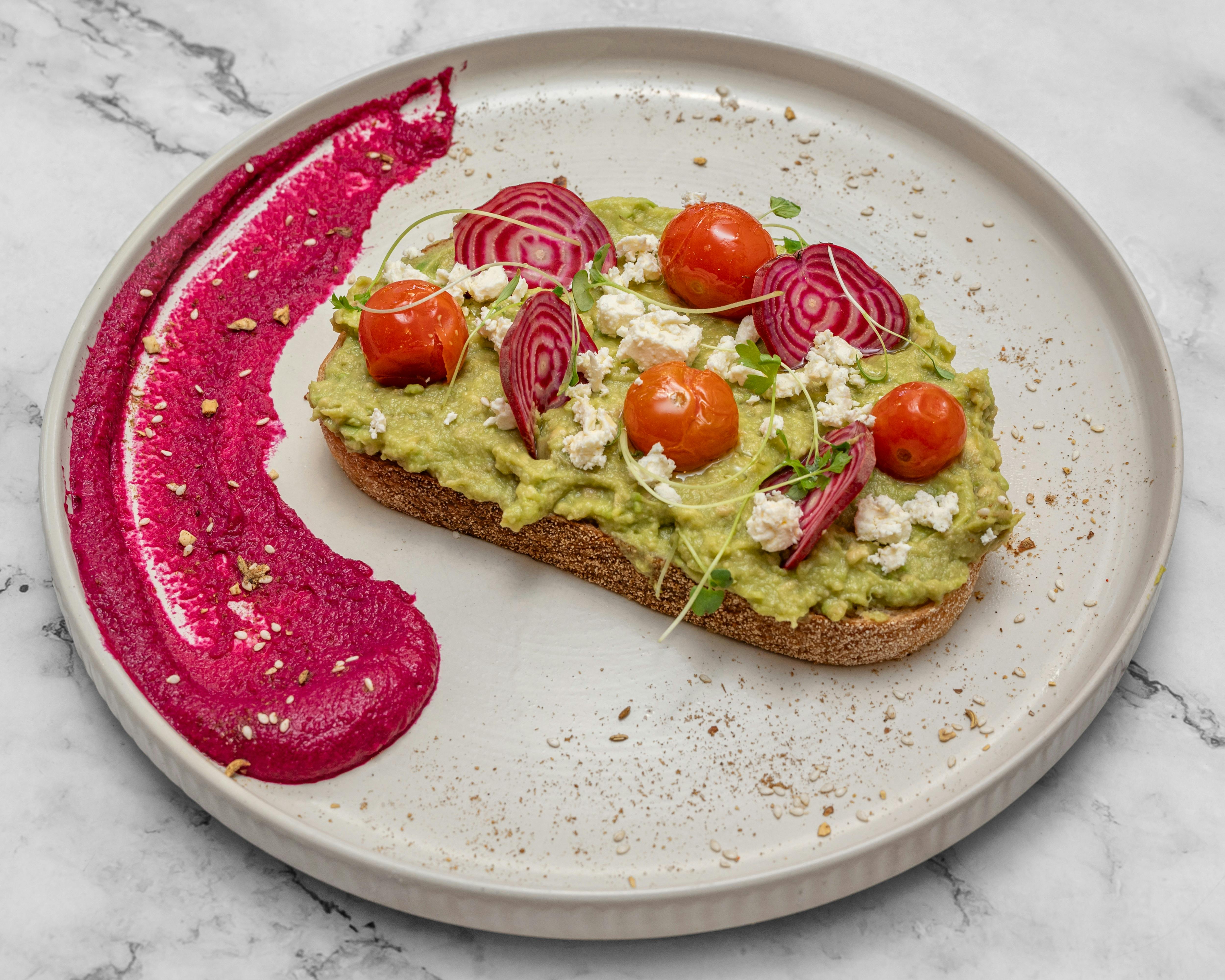 Smashed Avocado served with beetroot humus, cherry tomato, and feta cheese