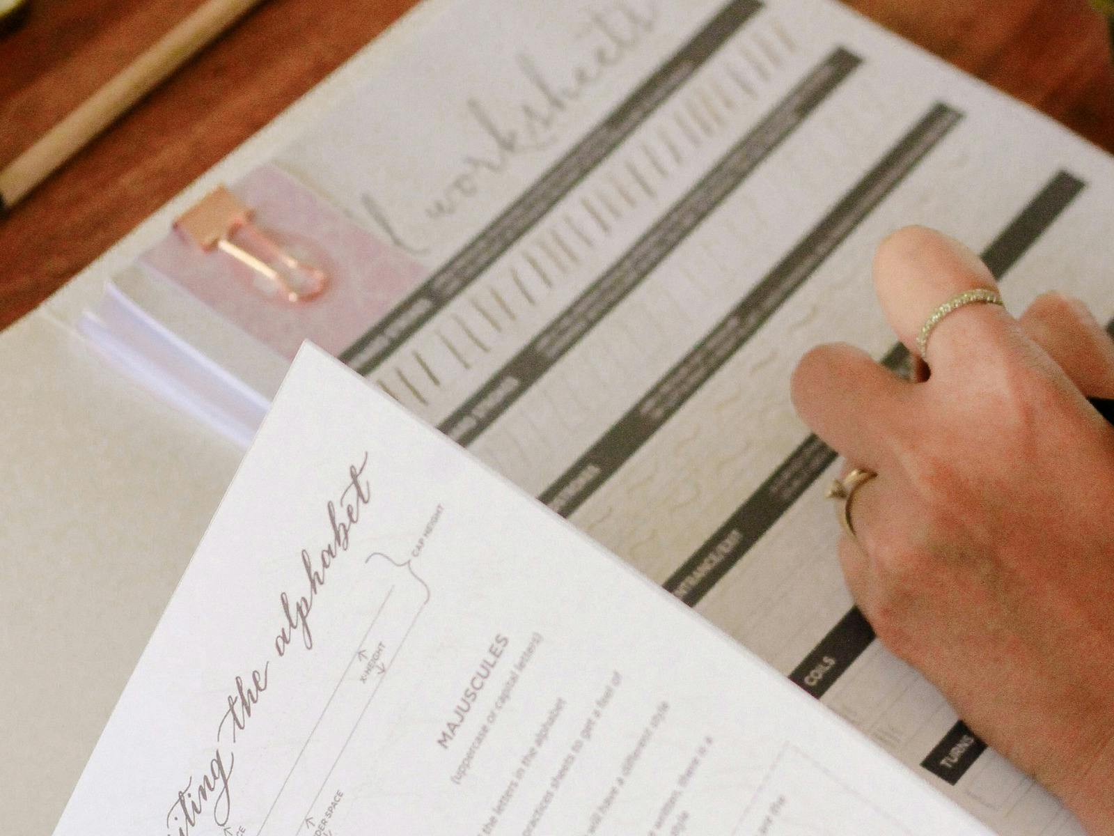 persons hand shown practising calligraphy on a template