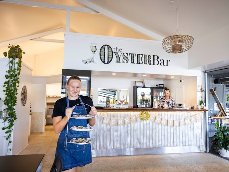 Waitress emerges from The Oyster Shed kitchen with  a with a triple stack of delicious fresh oysters