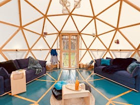 Interior of geodesic dome with two blue queen size fold out sofa beds.