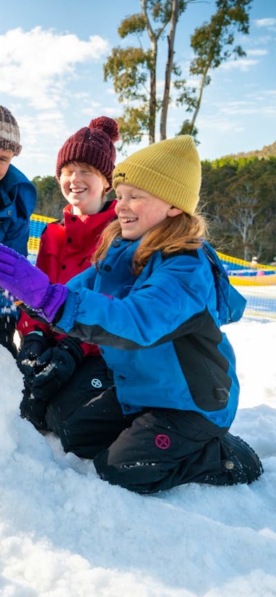 Mum, Dad, Daghter, and Son kneeling around a snowman which they are putting sunglasses on.