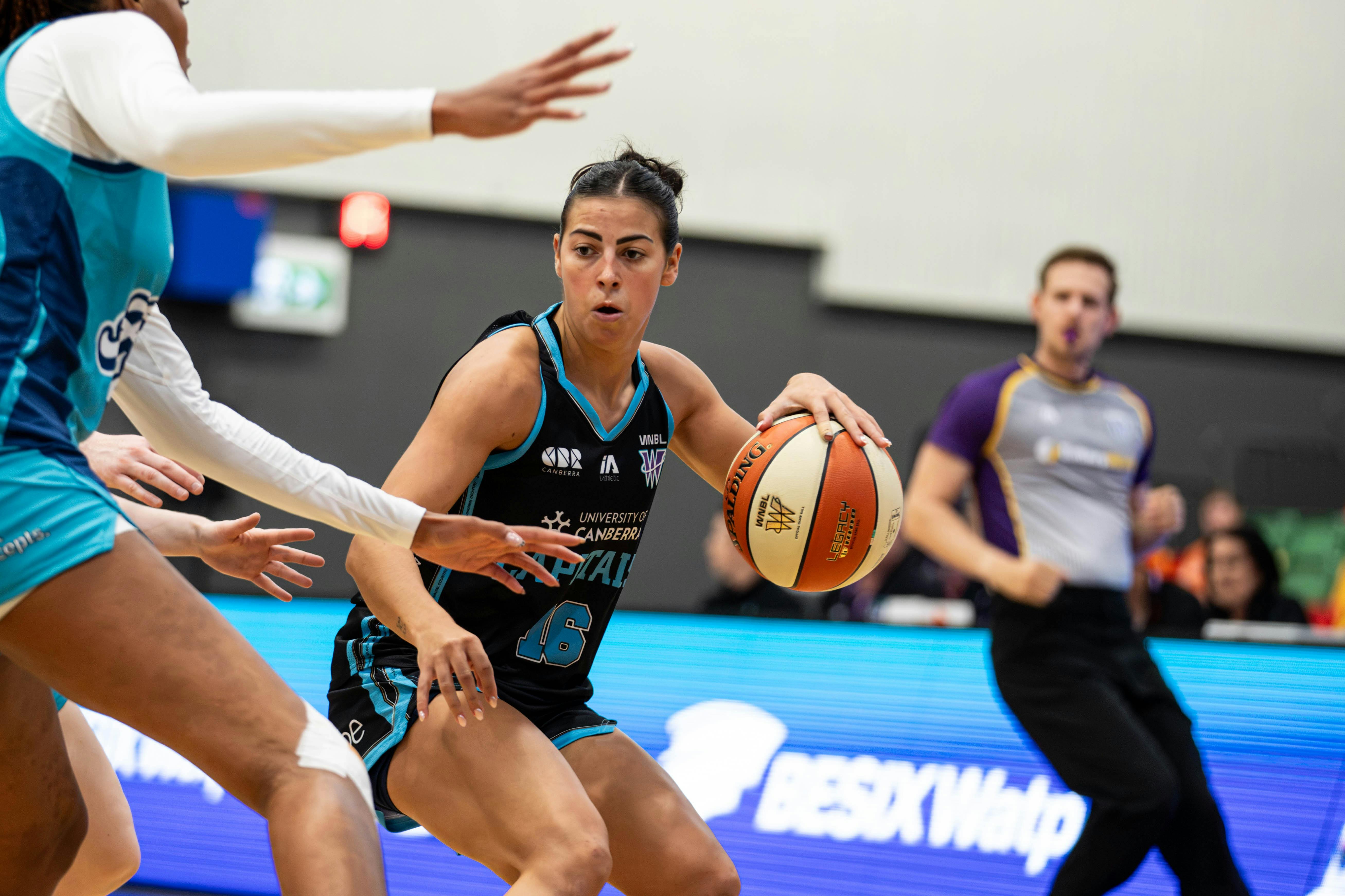 Female basketball player bounces the ball.