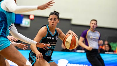 Female basketball player bounces the ball.