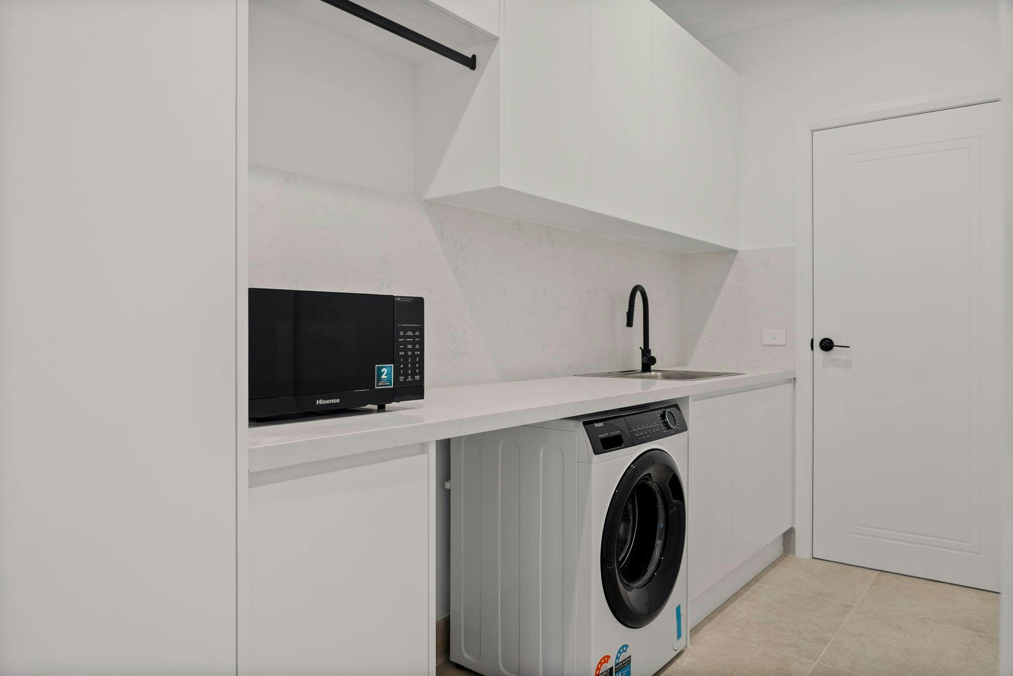 Laundry with washing machine, white cabinets, and black features