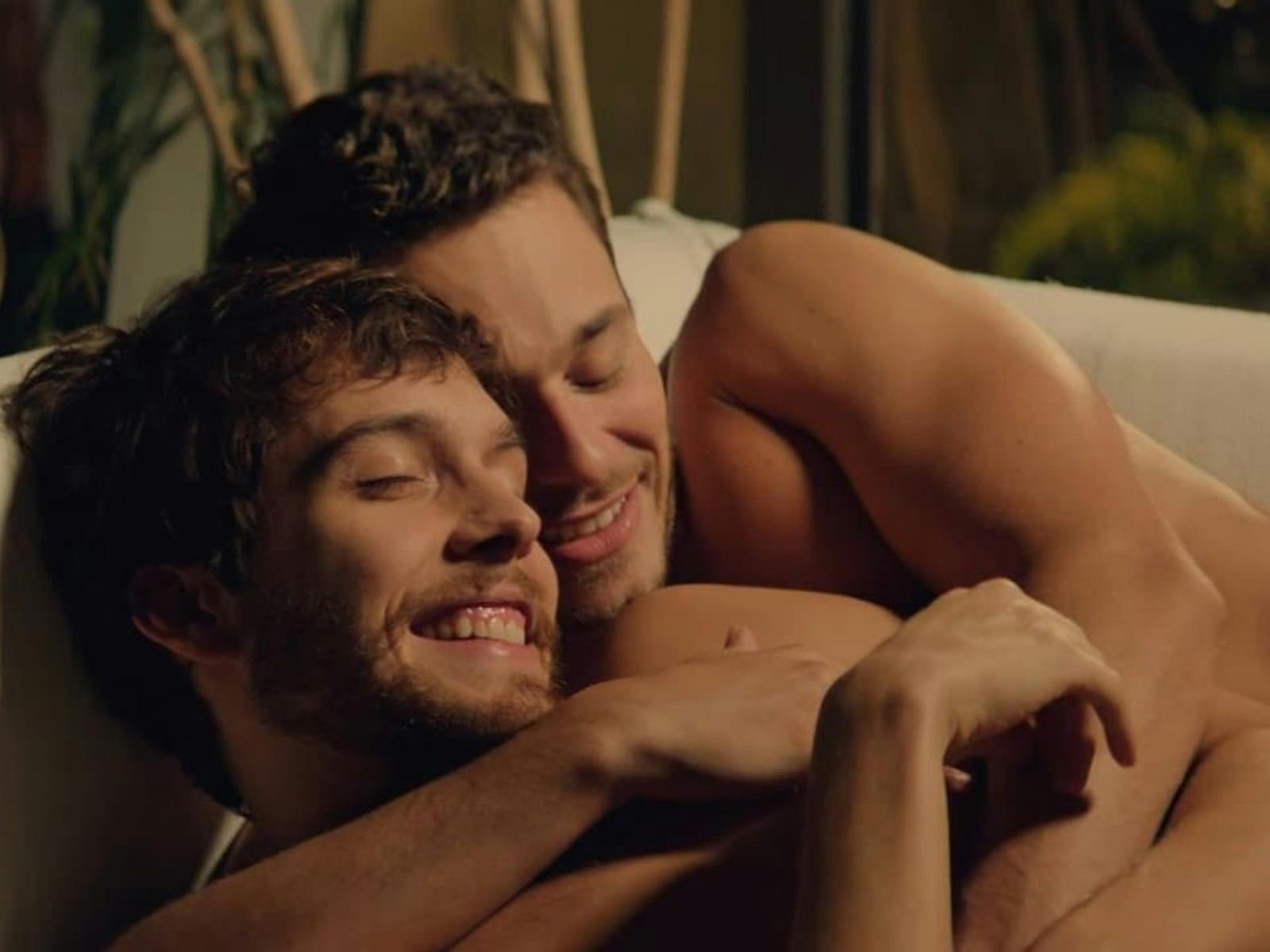 Two men are cuddling on a couch.