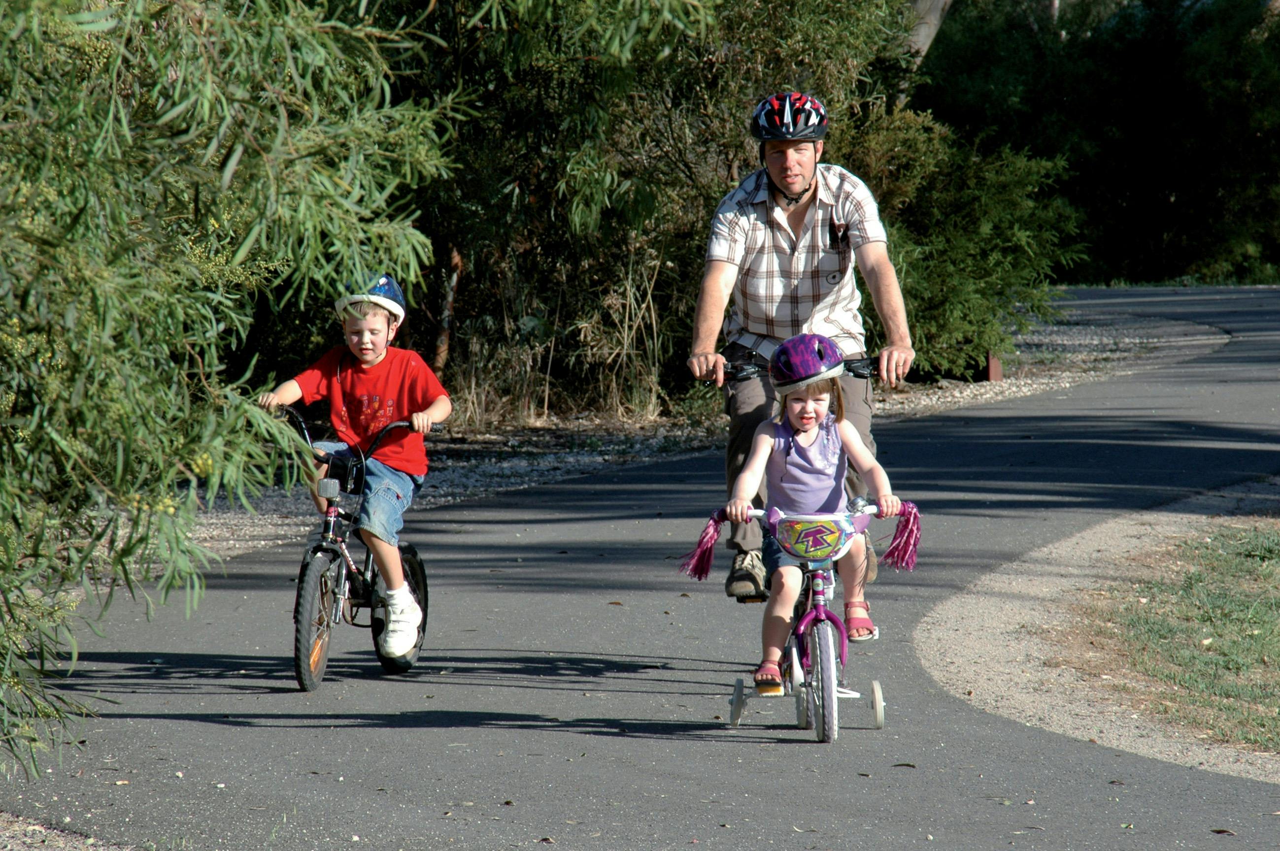 Man and two children cycling on path at Laratinga Wetlands