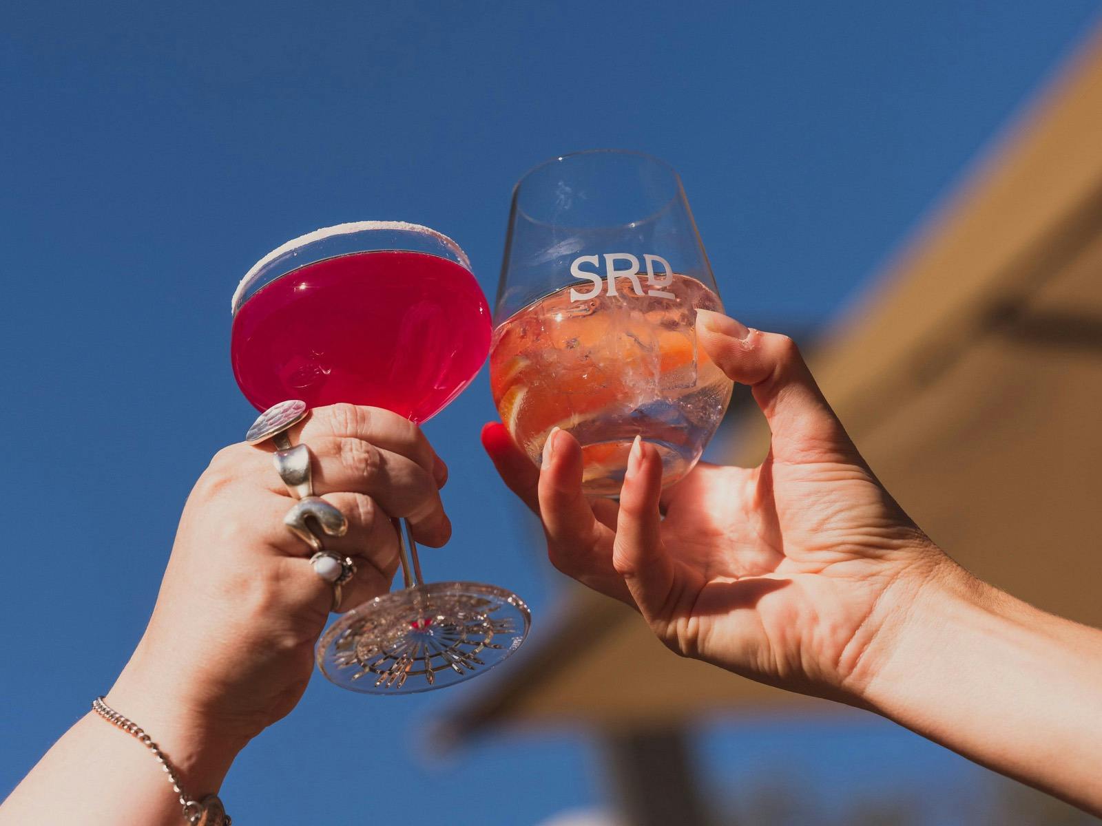 two glasses of cocktails in hands