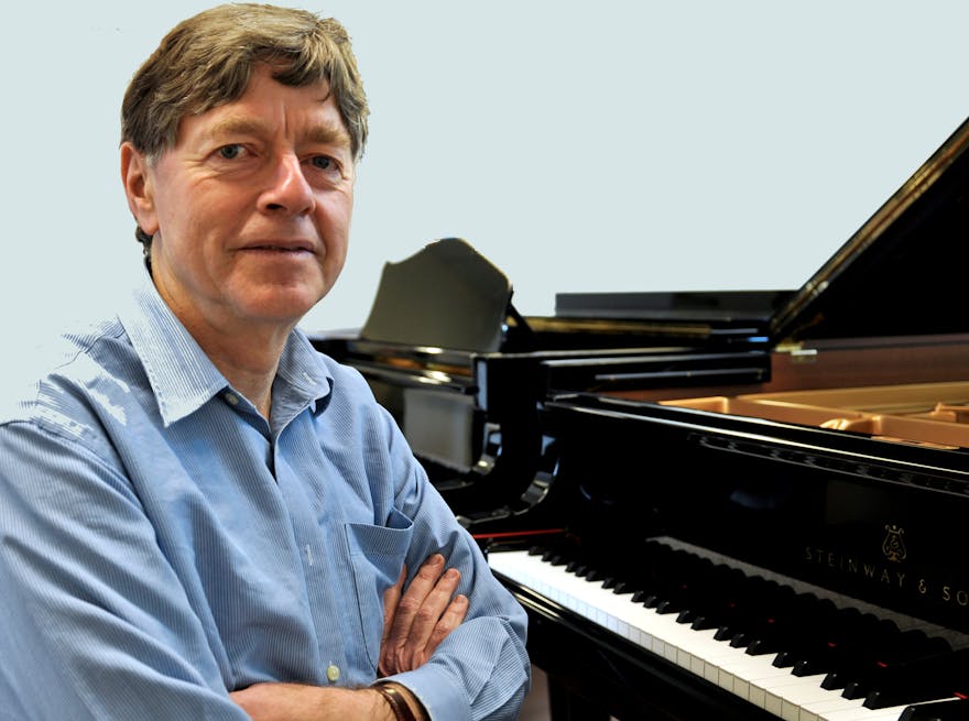 Daniel Herscovitch sitting at piano with arms folded