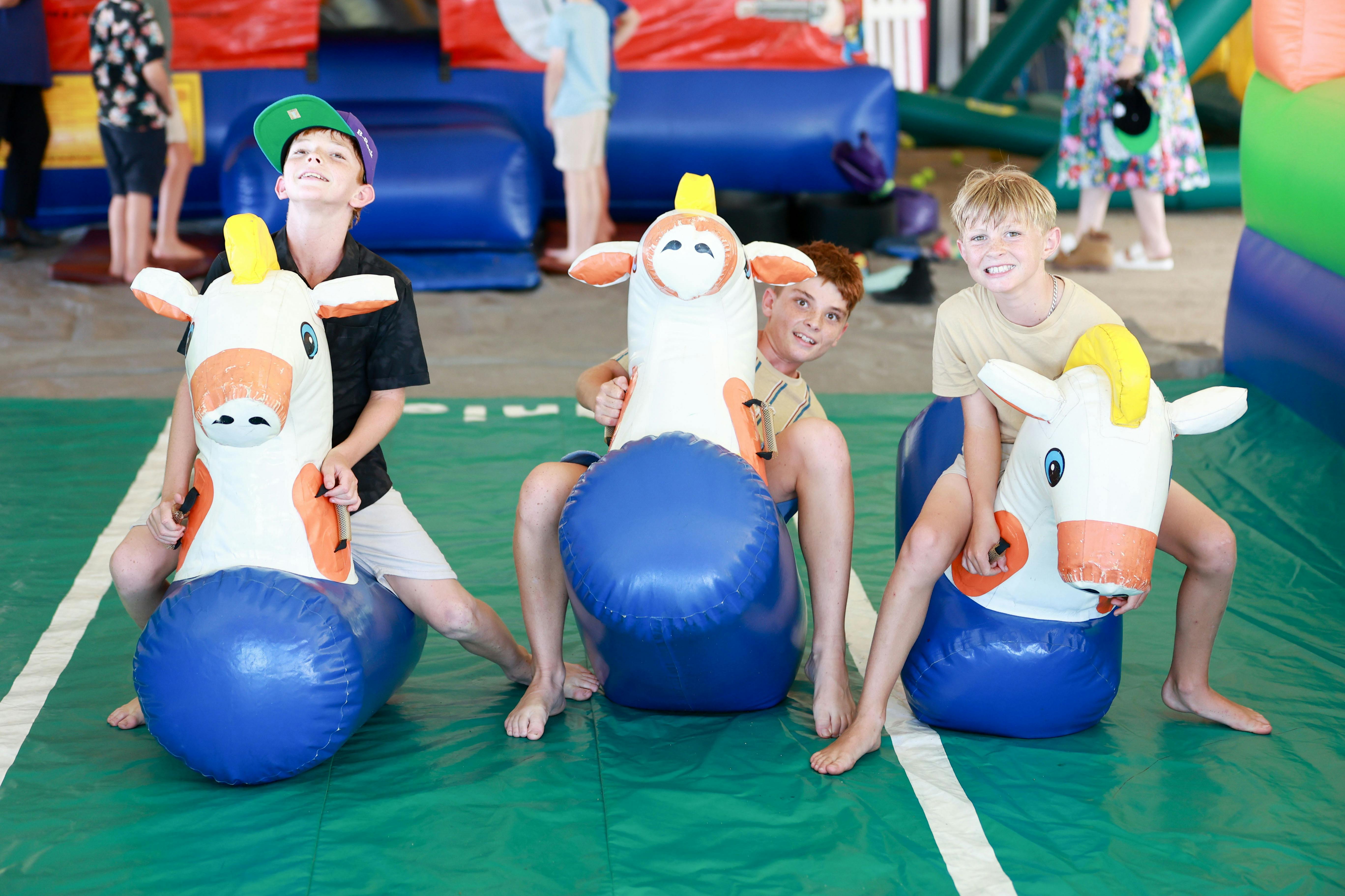 Three kids on colourful inflatable horses racing