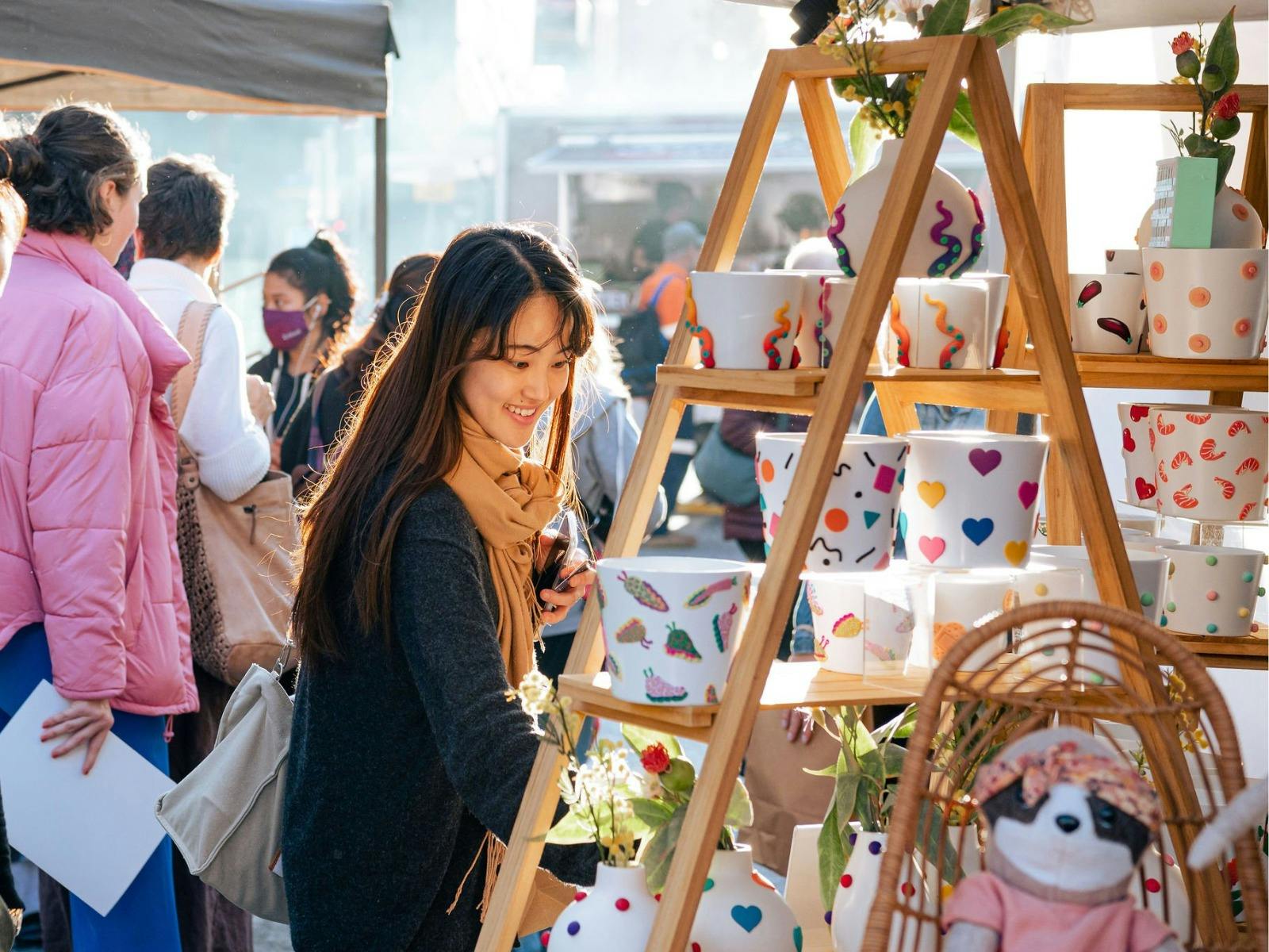 A woman smiling as she shops at a colourful plant pot stall