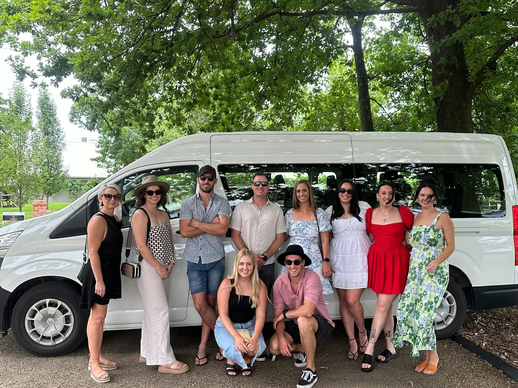 Picture is of a group of friends on a tour in front of bus