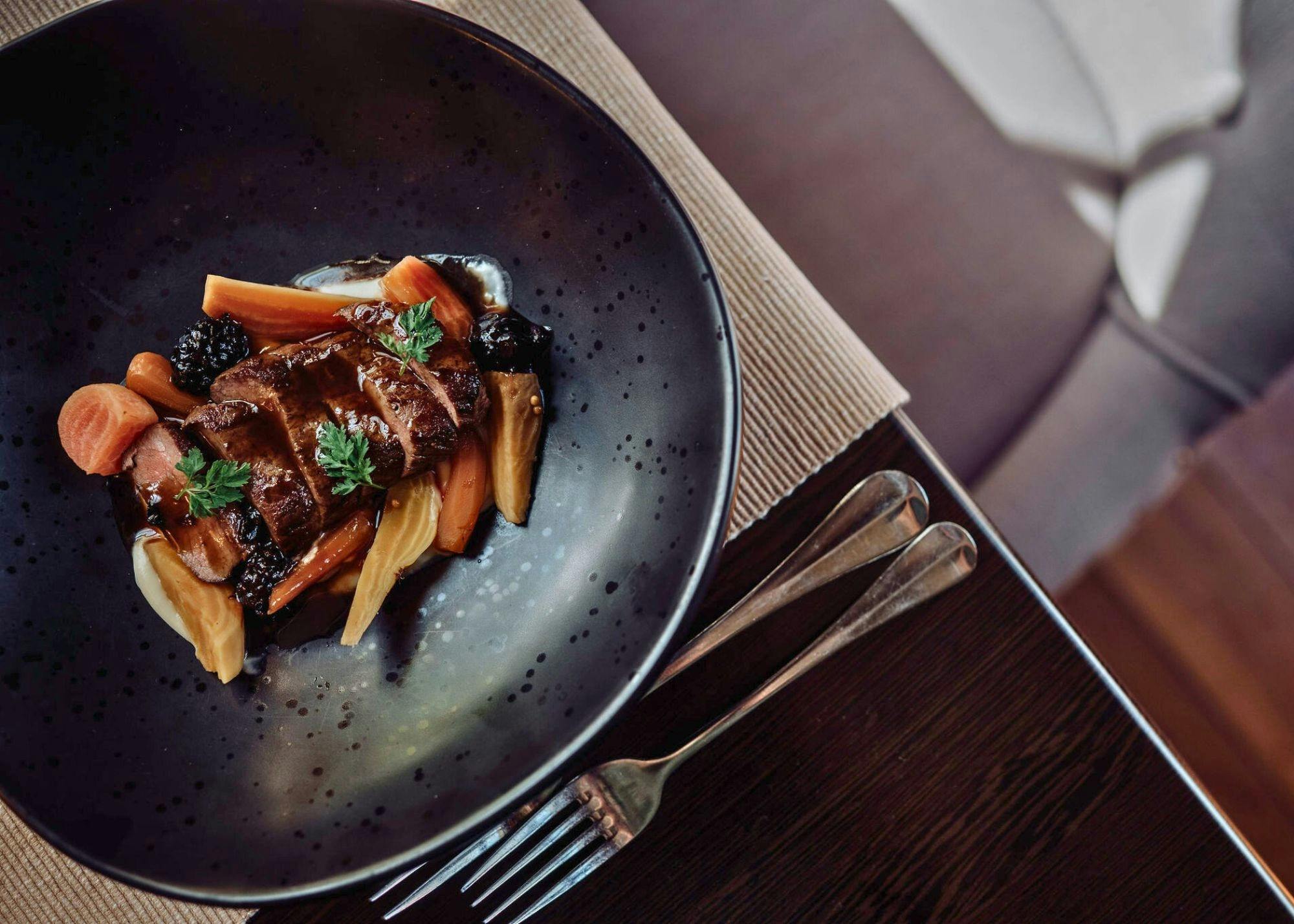 Venison meat served with carrots and wildberry jus