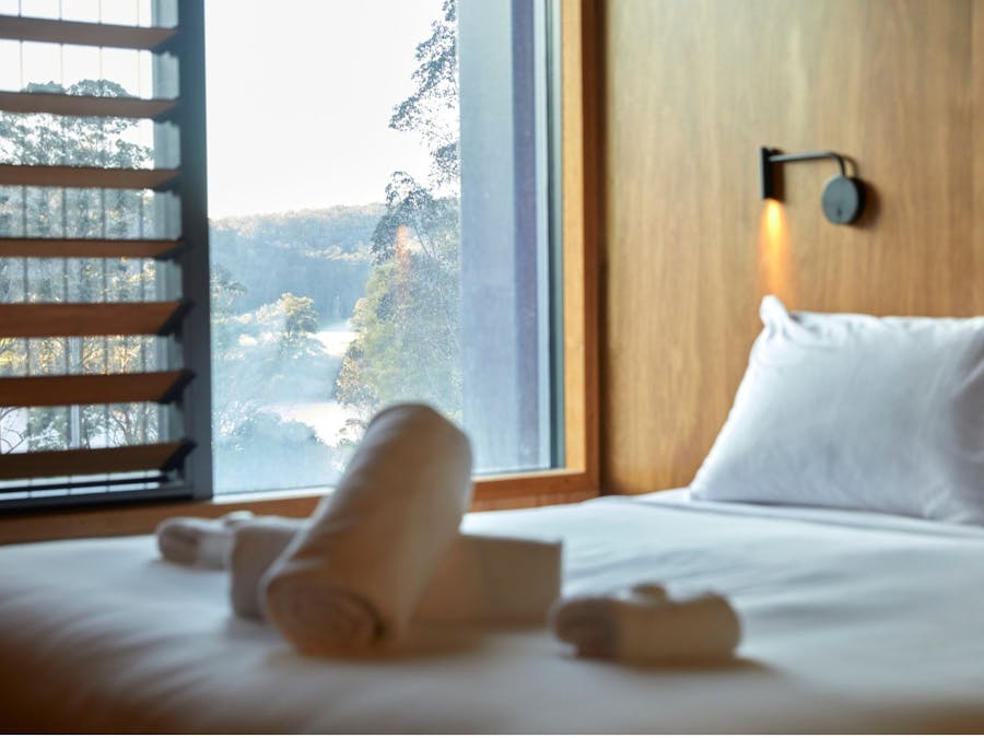 An interior photo of a timber paneled room with a view of the bed and misty outlook from the window