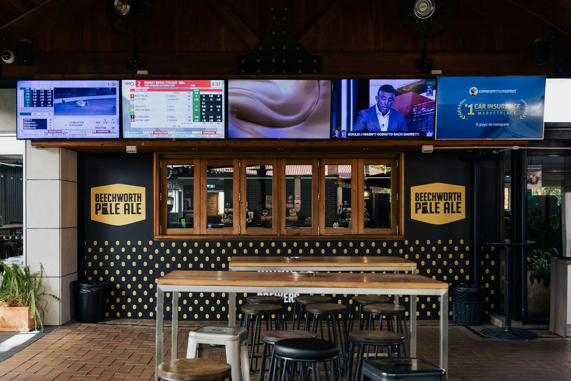 Undercover seating area facing toward a large bar window and multiple TVs