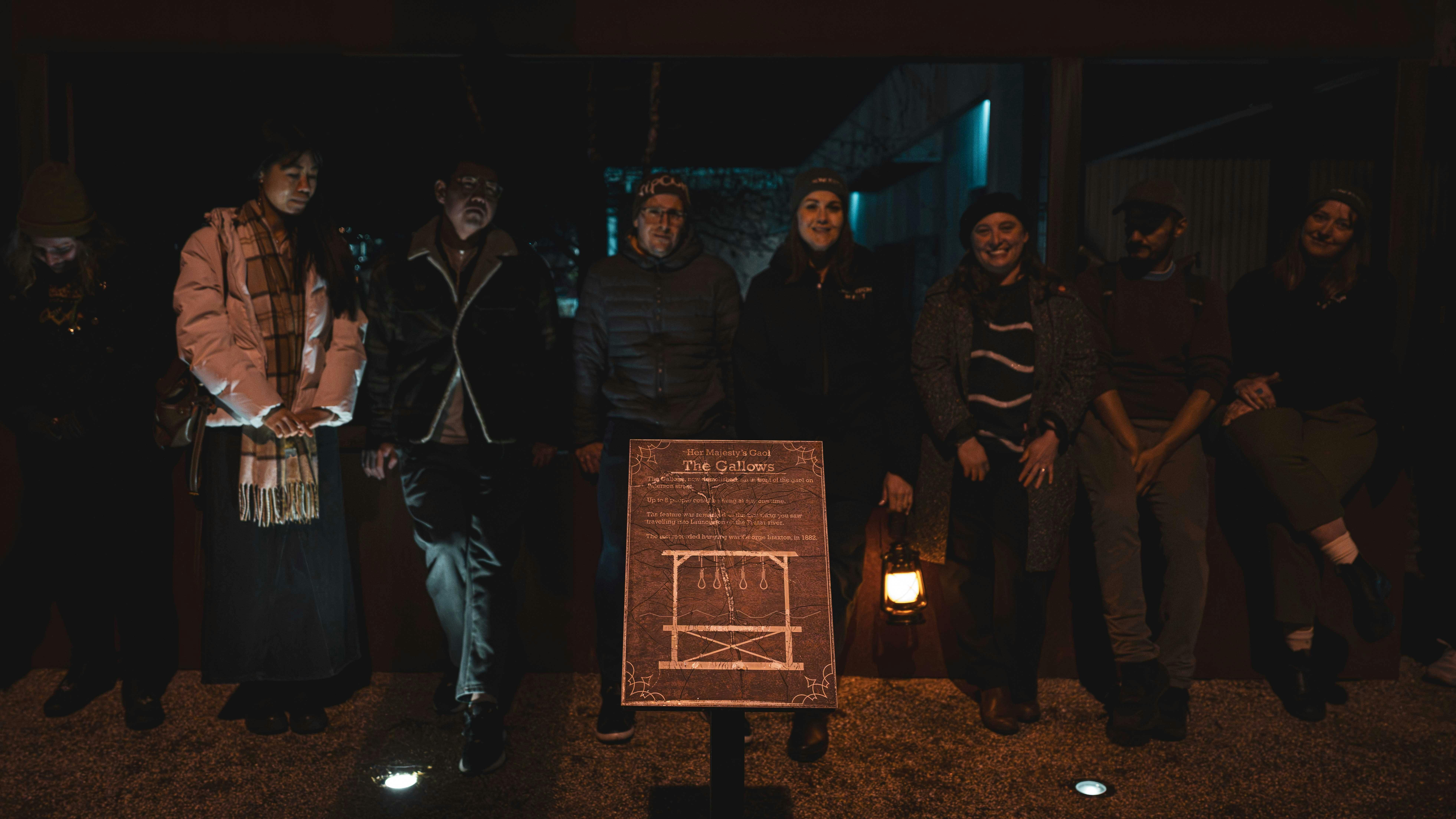 Dark Side of Launceston tour group gathered around the illuminated Gallows historical interpretation