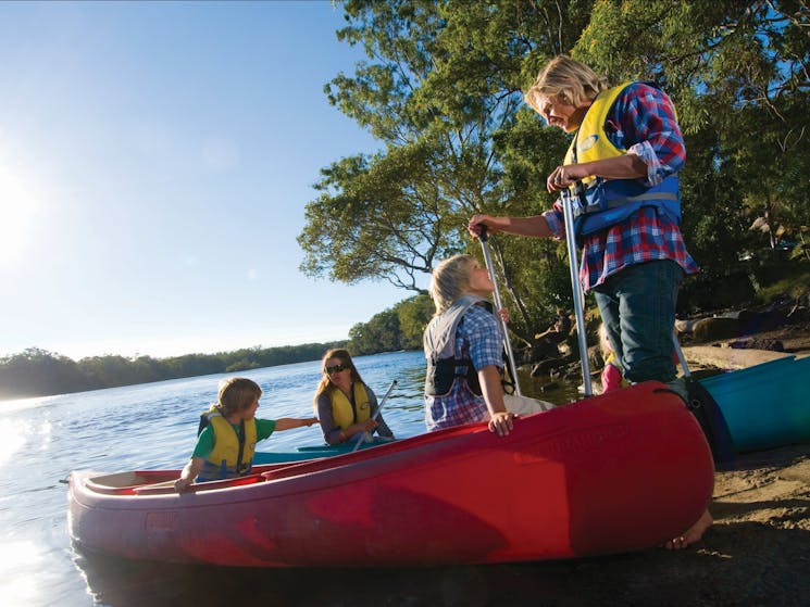 Canoes with people on river bank