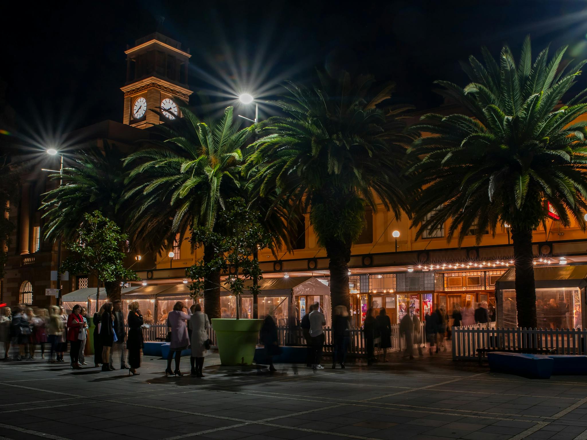 Photo of the Civic Theatre at night . Lights illuminate the building. A crowd stands in front.