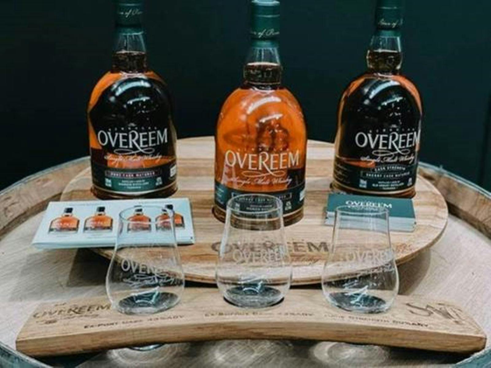 three Overeem Whisky bottles behind a tasting flight with three glasses