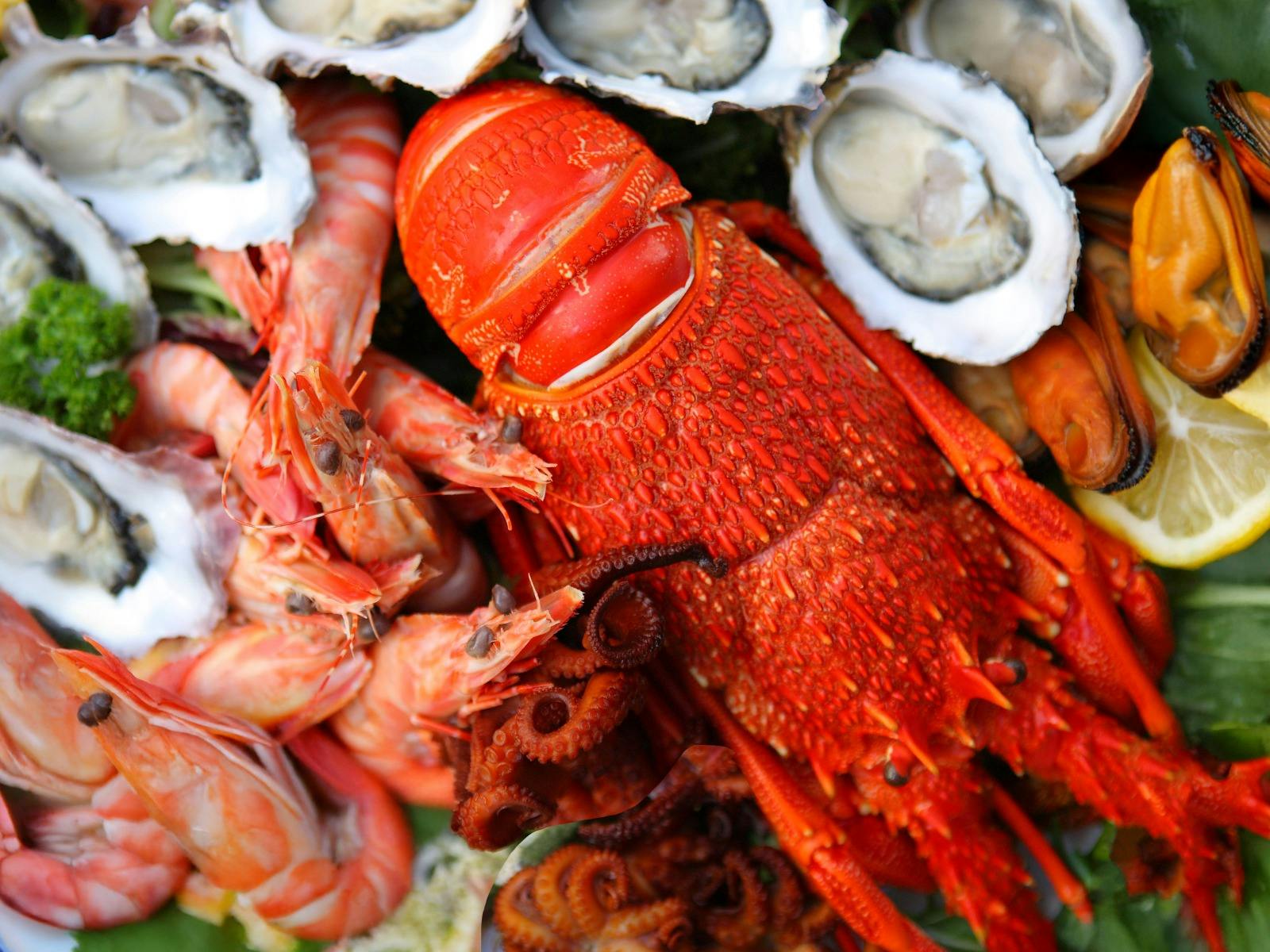 A medley of fresh and cooked seafood, including prawns, rock lobster, oysters, and smoked mussels.