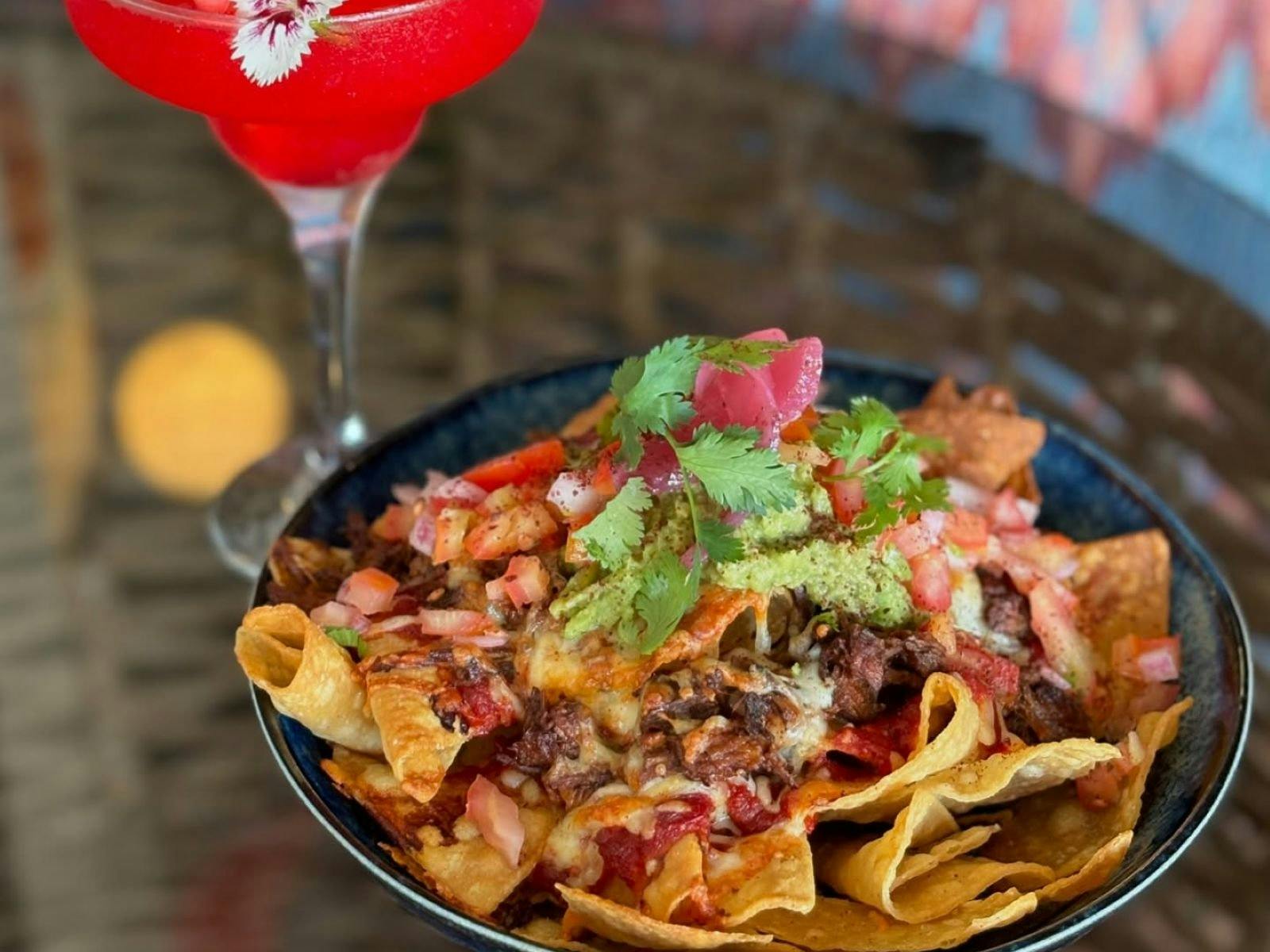 big plate of nachos and red cocktail