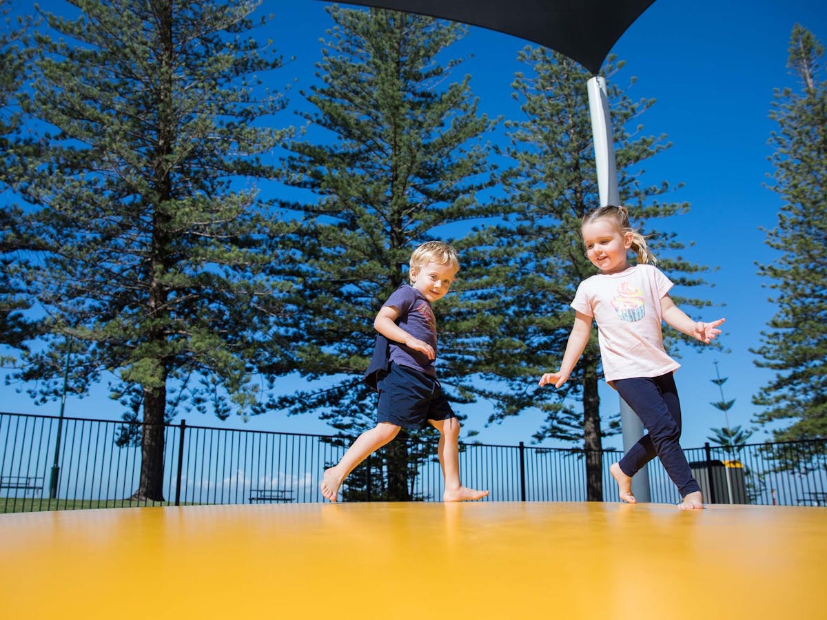 Two young children playing on the jumping pillow