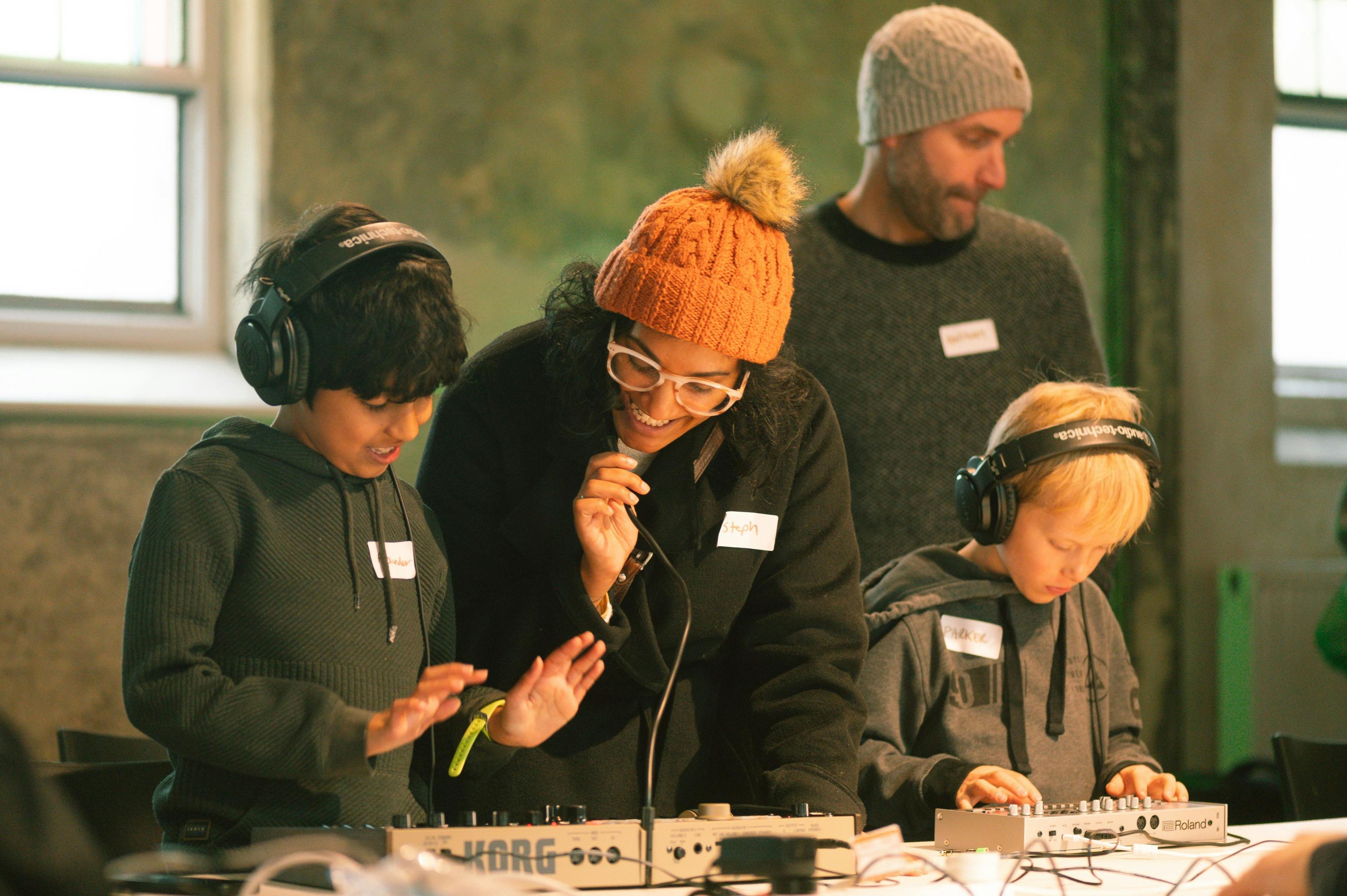 Parents and kids with synthesisers during electro music workshop