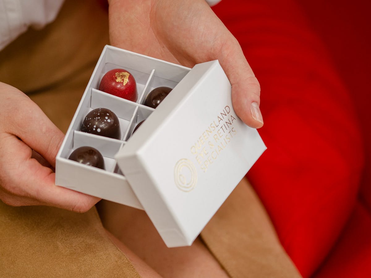 womens hands holding an open box of chocolate pralines
