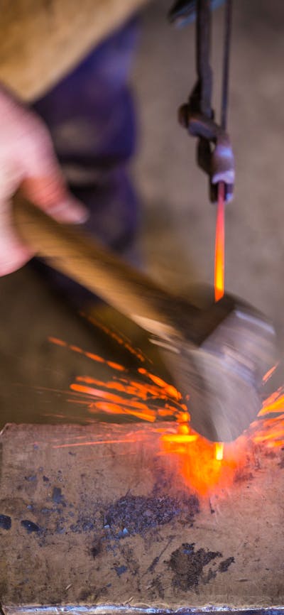 blacksmith striking hot metal on an anvil with sparks flying