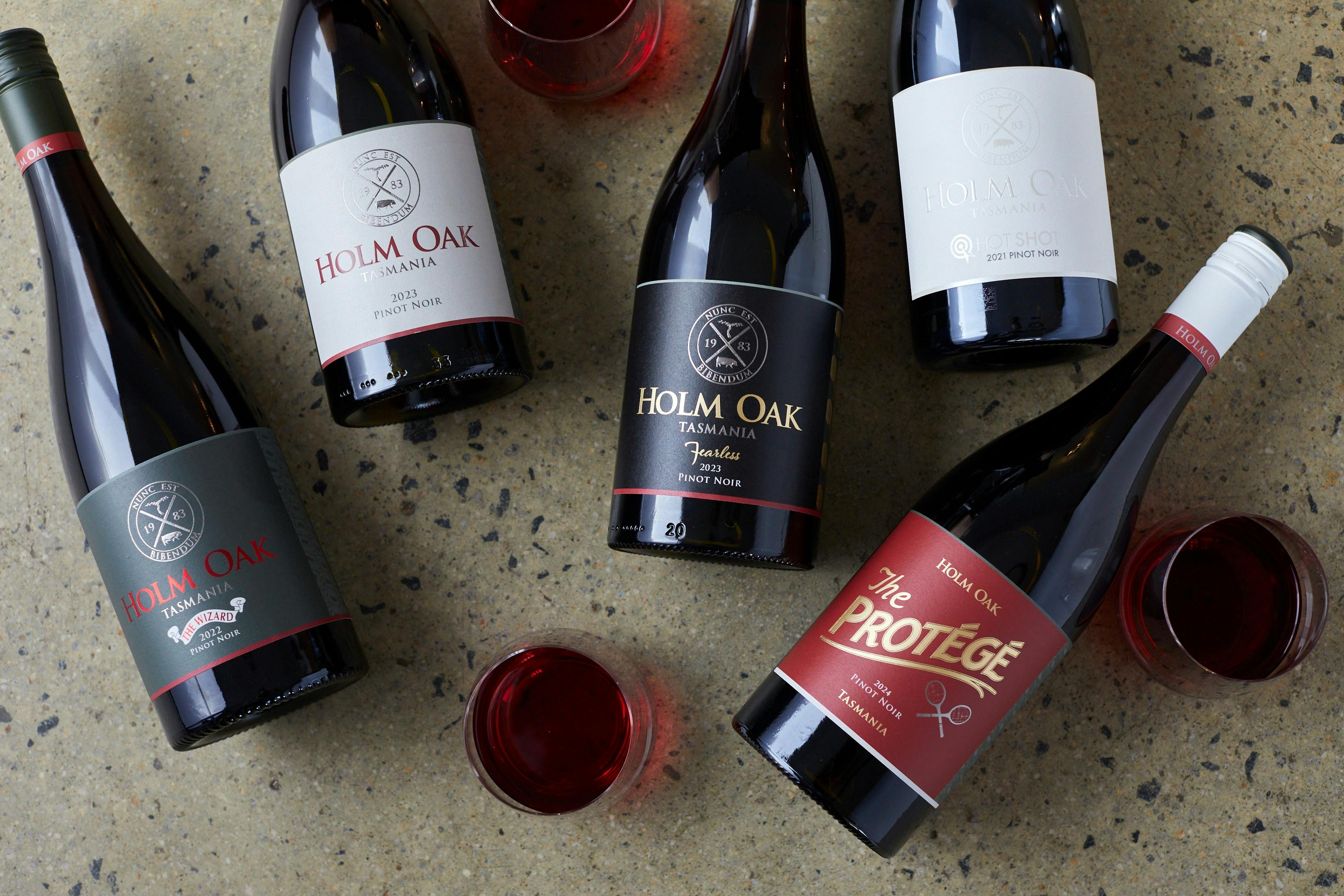 A flat lay of the 5 different Pinot Noir wines on a concrete background