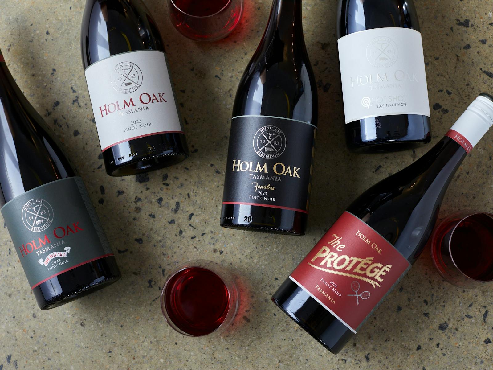 A flat lay of the 5 different Pinot Noir wines on a concrete background