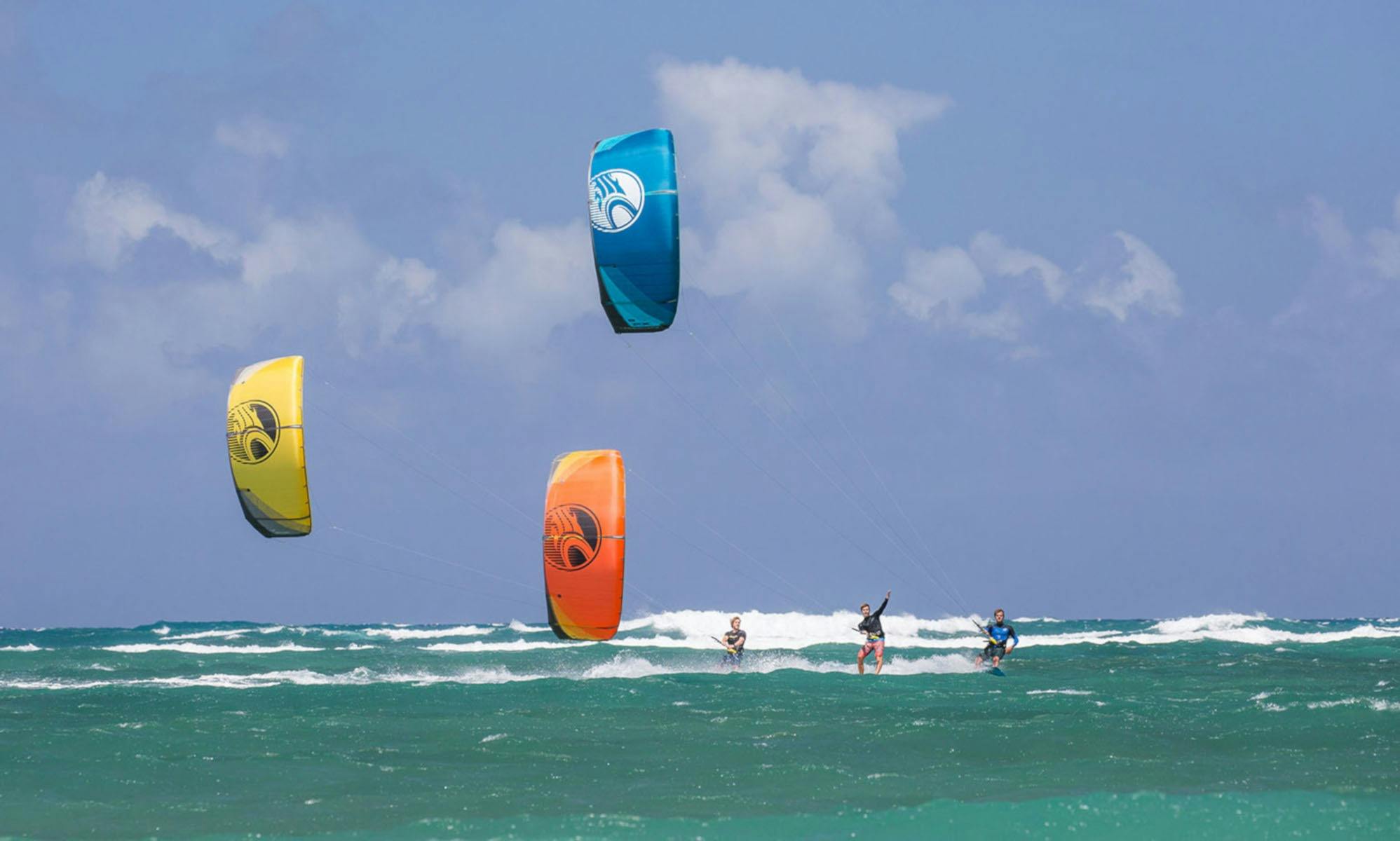 3人のカイトボーダー全員がビーチに向かってサーフィンしています