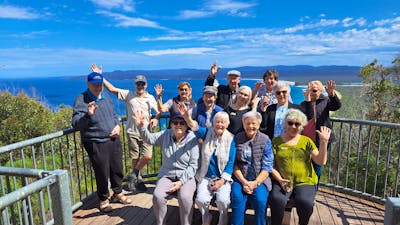 several seniors on lookout platform with ocean and bay behind