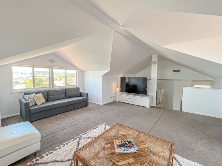 The upstairs attic room with its soaring ceiling is a stunning light filled space to get away from i