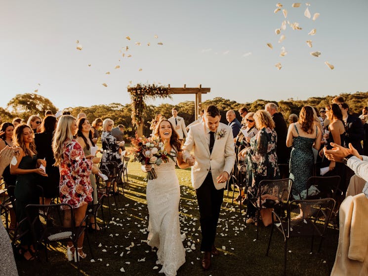 Bride and Groom walk back down aisle after being married whilst friends and family throw petals