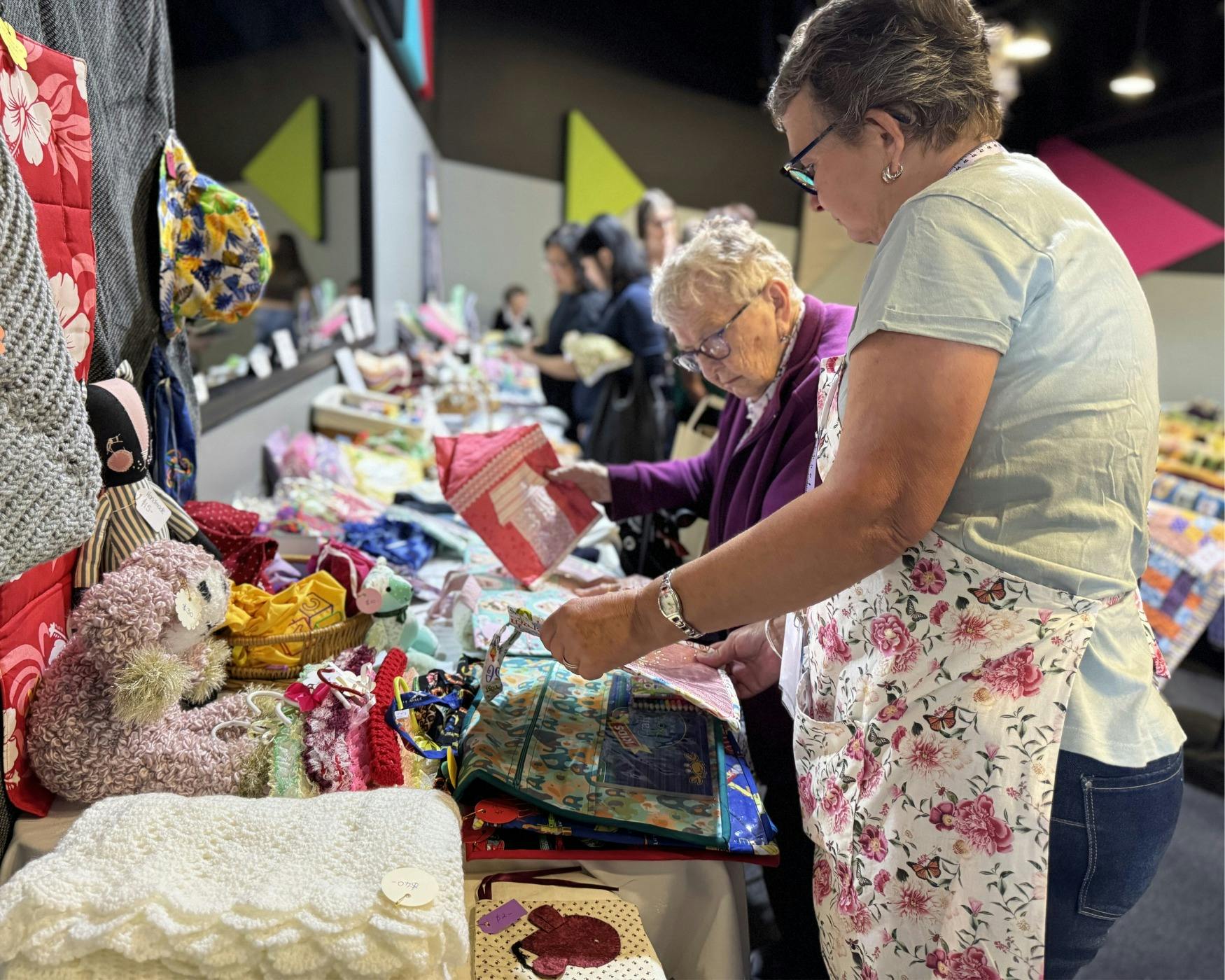A helper and visitor browsing craft display table