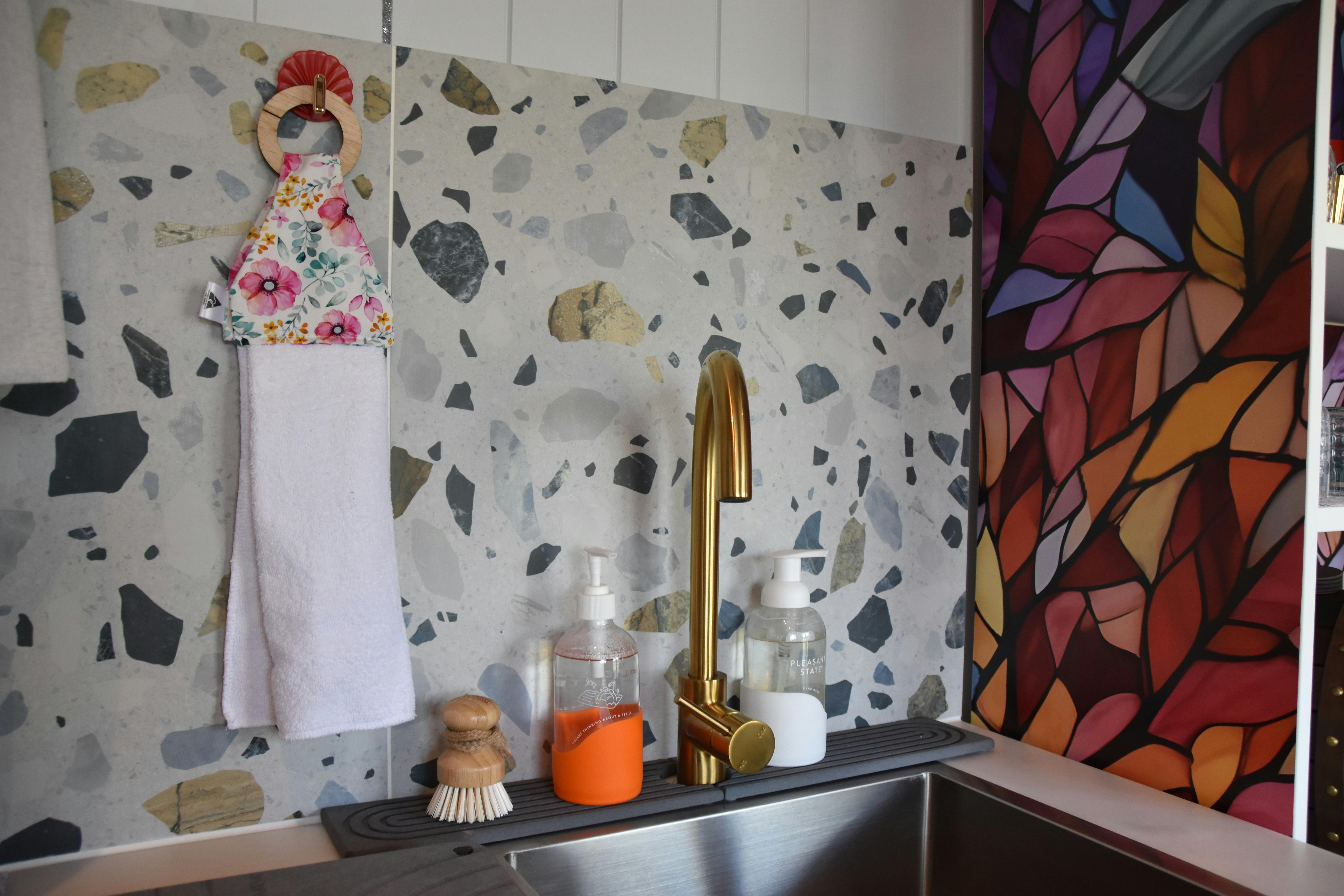 Kitchen sink with brass tap and terrazzo splashback.