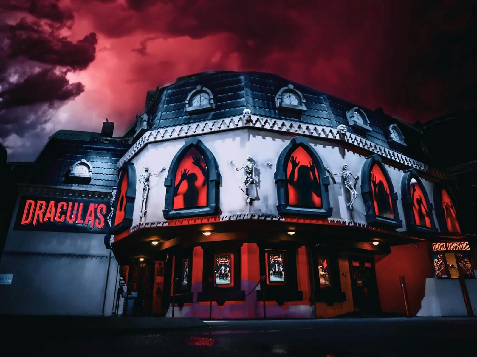 Exterior of Dracula's Gold Coast at night, featuring gothic architecture and glowing red windows