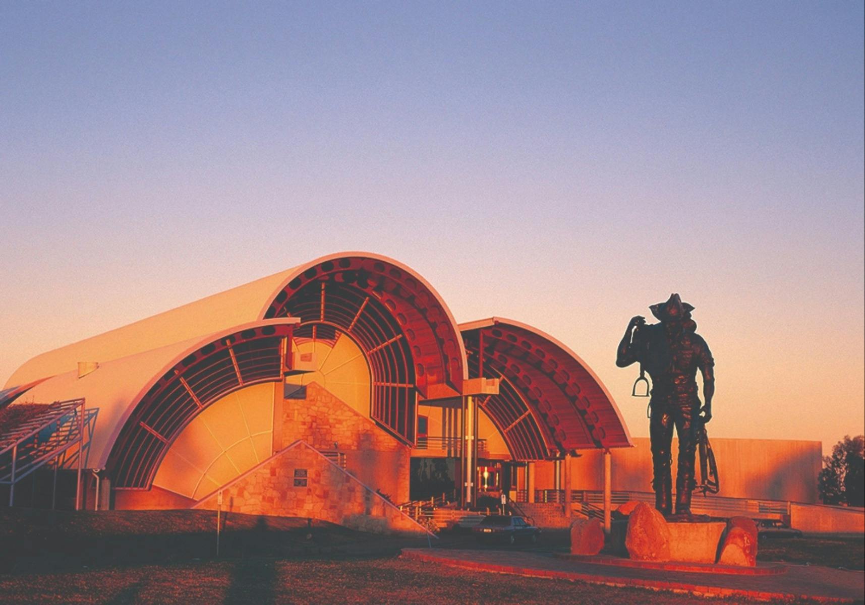 the stockman in front of the arched roof of the Australian Stockman's Hall of Fame