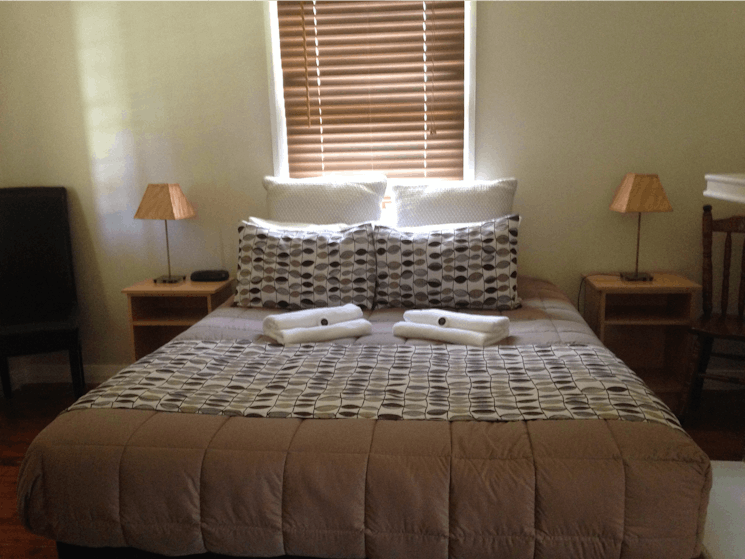 Bed with bedside tables and lamps on both sides of bed.