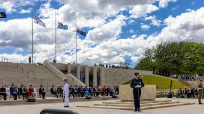 Flags at half mast, stone of remembrance and soldiers standing at each corner