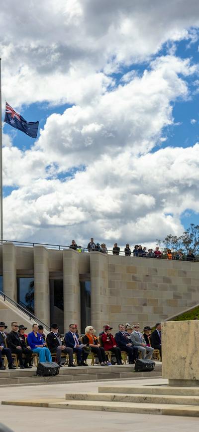 Flags at half mast, stone of remembrance and soldiers standing at each corner
