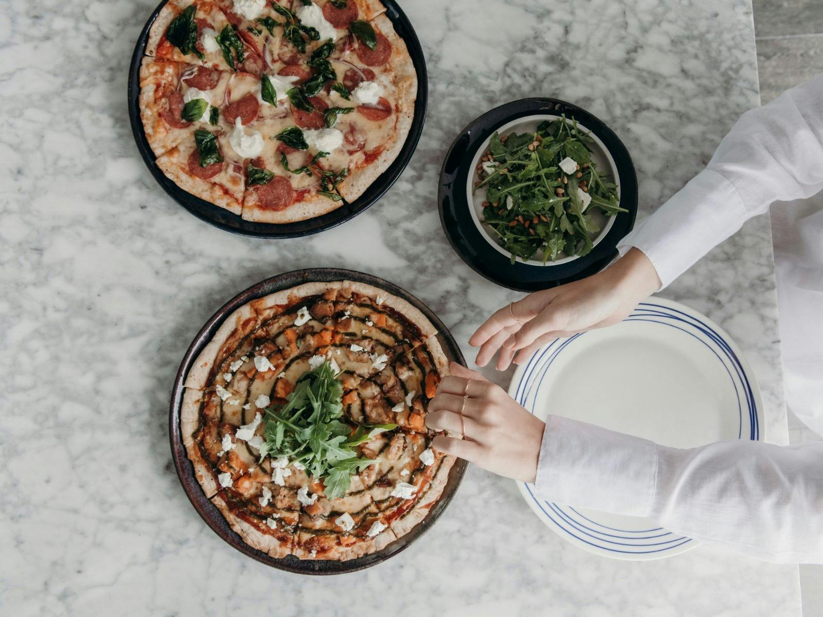 Woman's hands reaching for a slice of pizza