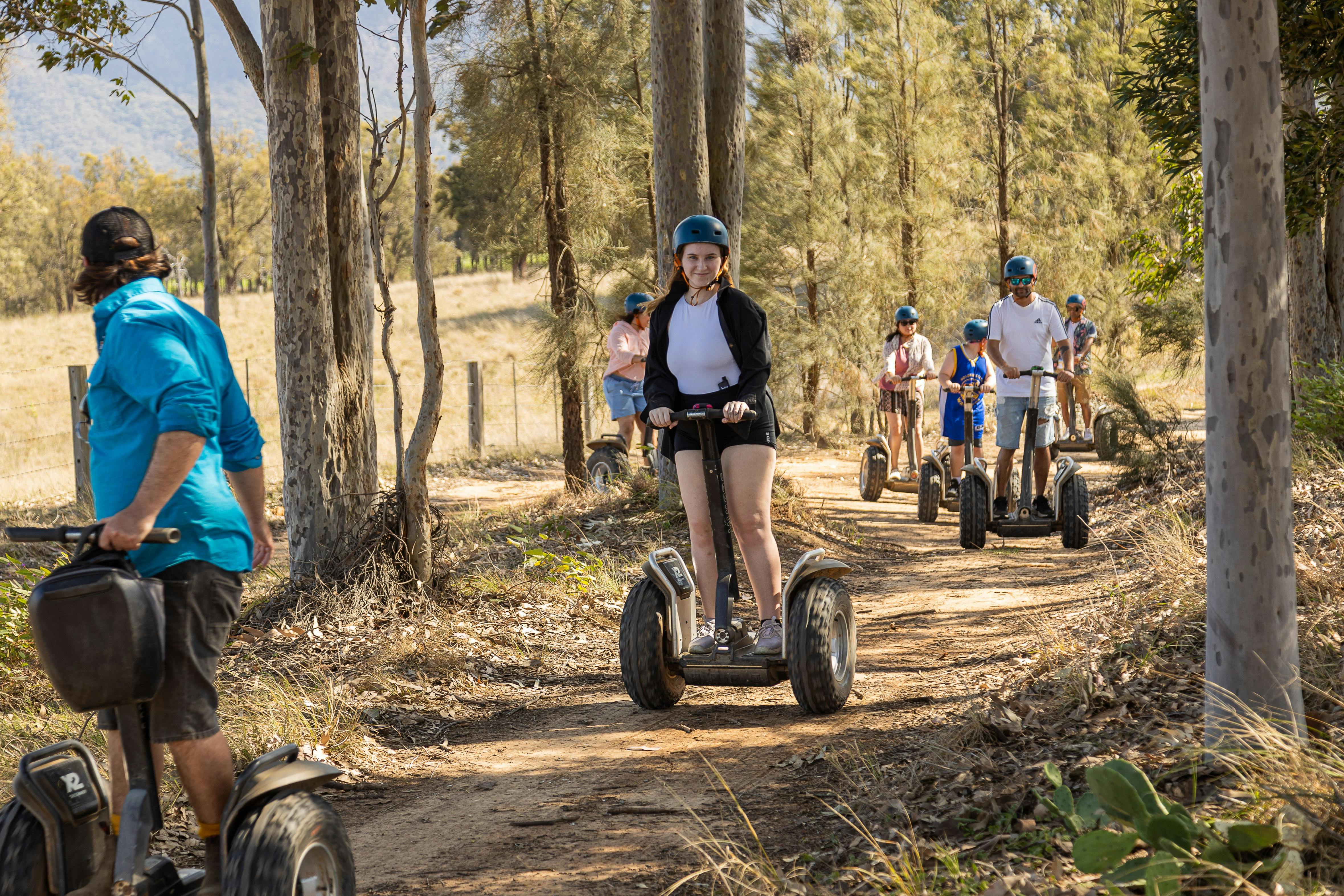 youth with helmets are riding sweats on a dirt trail throughout an Australian woodland setting
