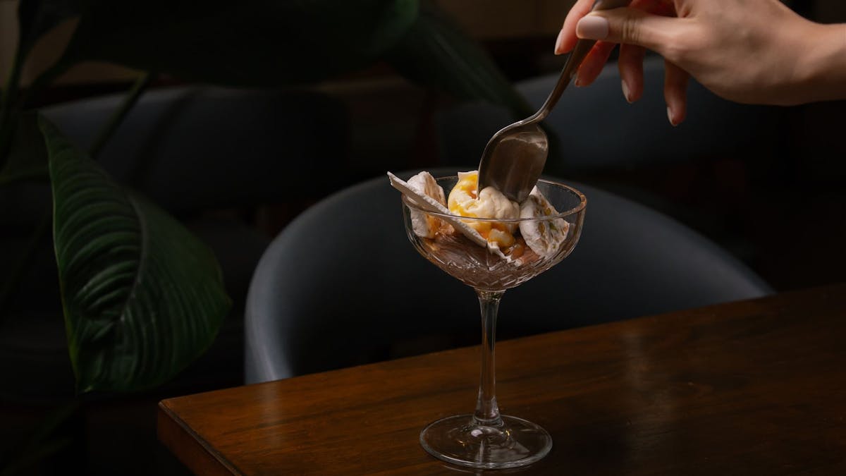 Hand with spoon in ice cream bowl Hand with spoon in ice cream bowl