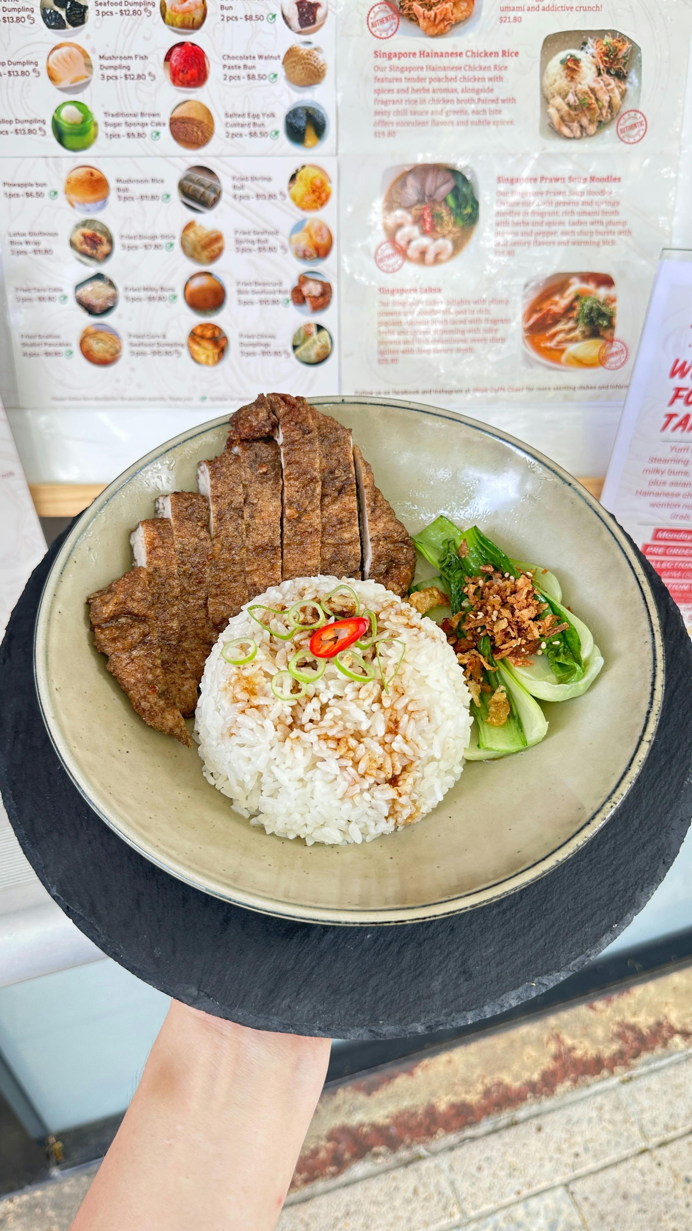 Crispy sliced fried pork chop on fragrant rice with greens and chili topping.