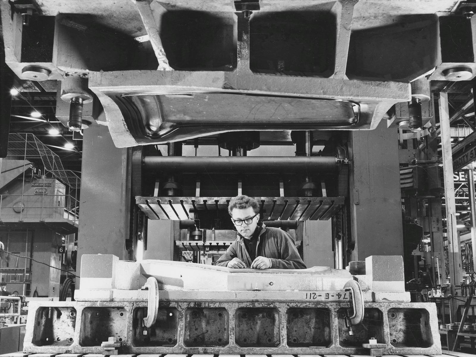 Black and white photograph of of a mechanic working on a Holden car